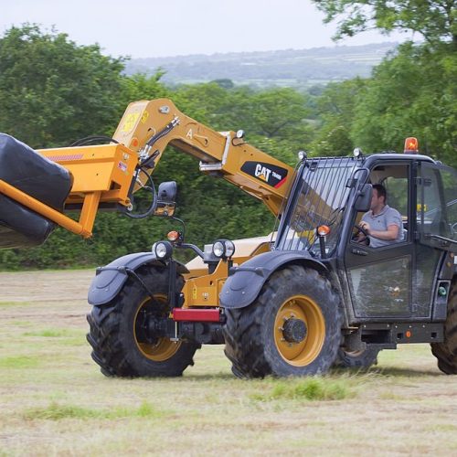 Nr Narberth, Pembrokeshire, Wales - June 18, 2009: A CAT TH406 telehandler being used to drive wrapped bales of hay to a storage point.